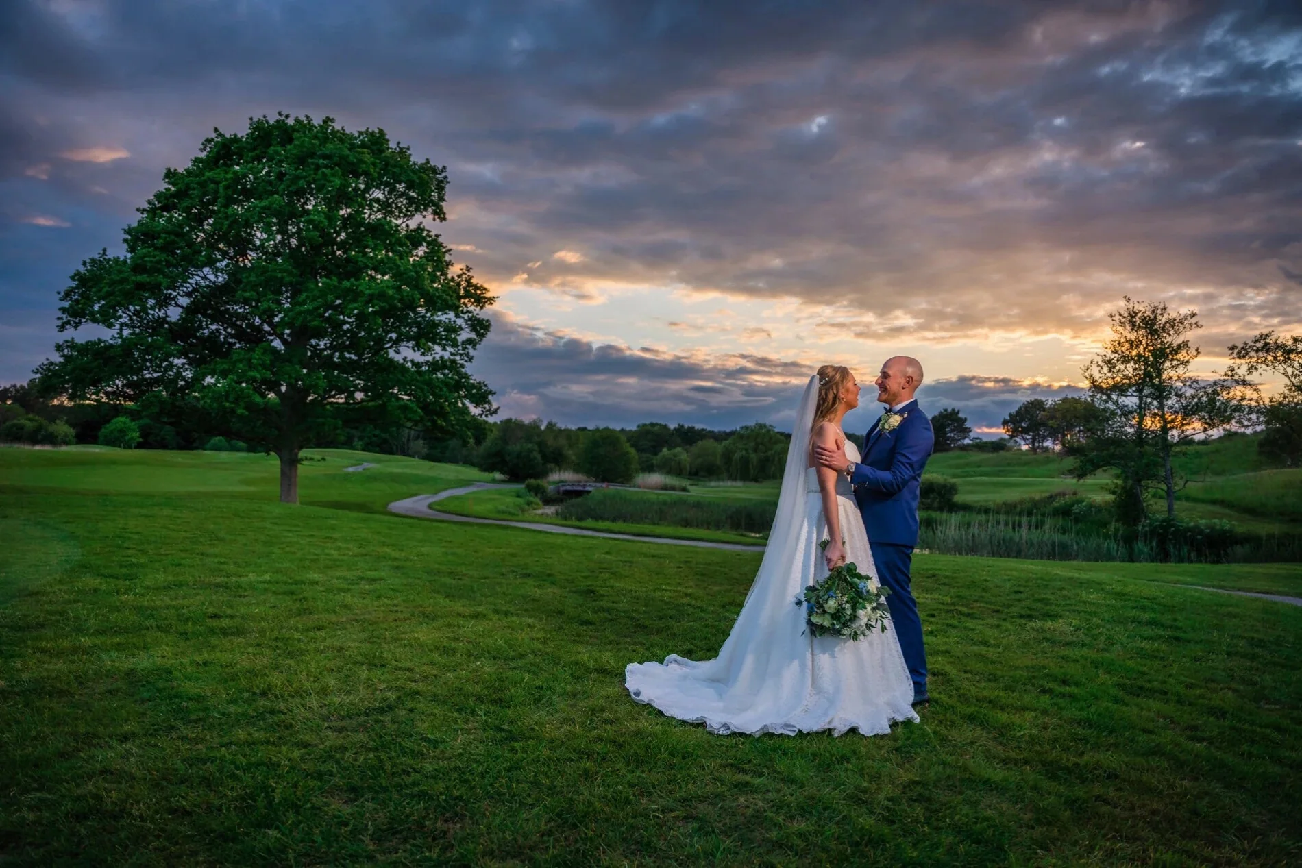 Bride and groom on a golf course fairway at sunset
