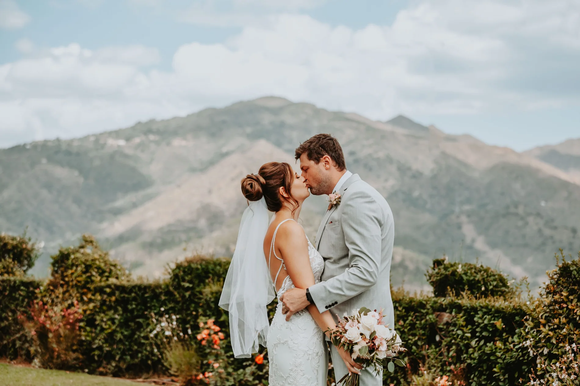 Bride and groom kissing with mountains behind them