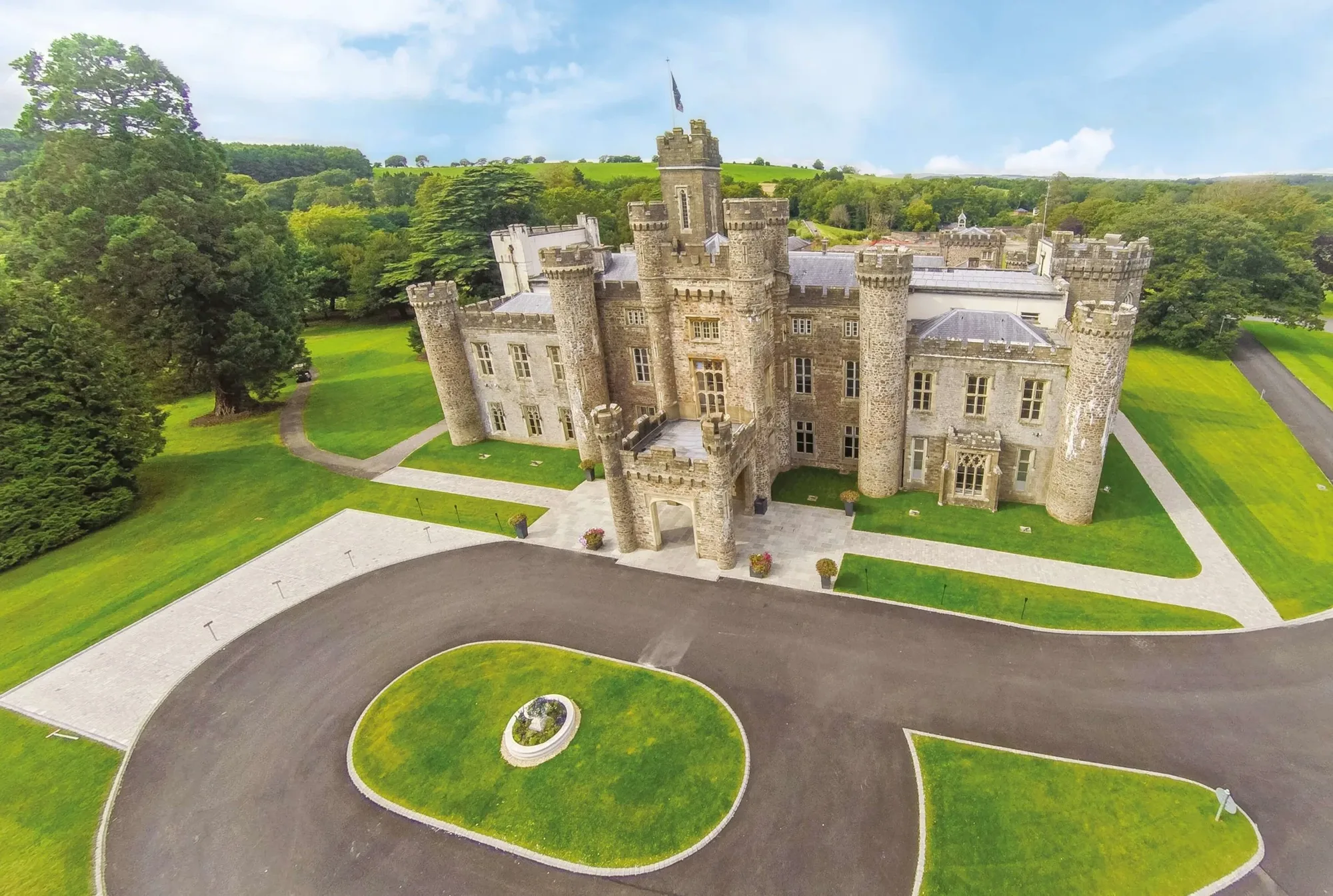 Aerial view of a turreted castle wedding venue in Wales, set in green parkland