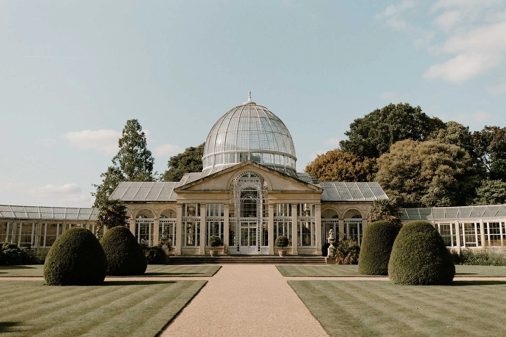 Glass-domed Georgian conservatory wedding venue in England with formal lawns and clipped topiary