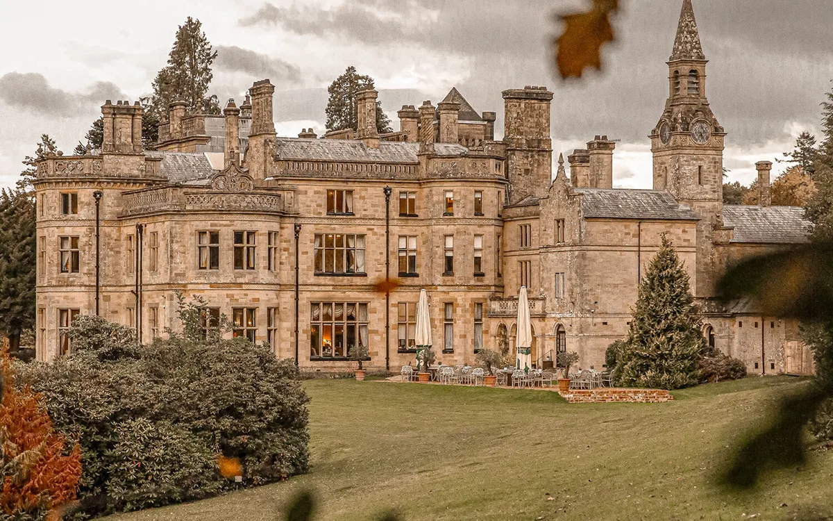 Victorian stone country house wedding venue in Wales with a clock tower and sweeping lawns in autumn