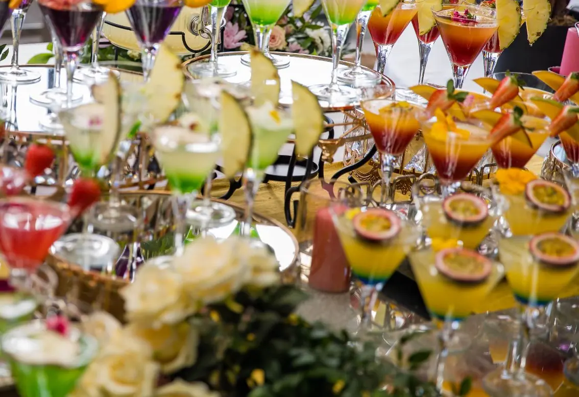 Colourful wedding cocktails garnished with orange, pineapple, strawberries and passion fruit on a welcome drinks display