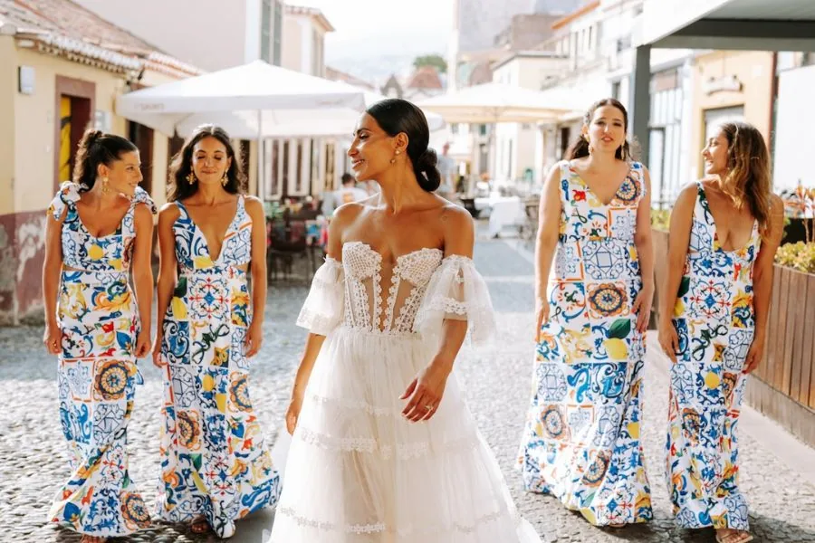 Bride and bridesmaids in printed dresses on a sunlit street, an Algarve wedding in Portugal planned by Swish Soirées
