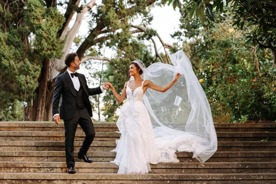 Bride and groom dancing on stone steps as her veil billows, a Spain wedding planned by Swish Soirées