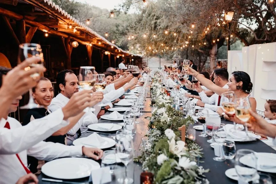 Guests raising a toast at a long outdoor table under festoon lights, a Spain wedding planned by Swish Soirées